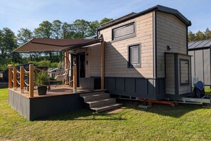 Ein Mobilheim mit Veranda, Treppe und einer kleinen Terrassenfläche.
