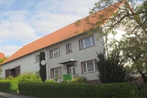 A two-story building with a red-tiled roof, a front entrance, and a sign indicating a business on the ground floor. - Holiday home in Blomberg with swimming pool (Blomberg)
