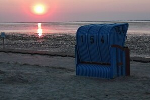 A beach chair with a number on it, positioned on the sand near the water. - Holiday home in Neßmersiel with Wi-Fi (Neßmersiel)