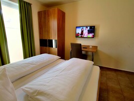 Una habitación de hotel con dos camas, un televisor en la pared, un escritorio y una silla.