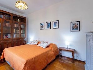 Ein Schlafzimmer mit einem großen Bett, einem Holzschrank, einem Nachttisch mit Lampe und drei gerahmten Bildern an der Wand.