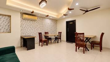A dining area with a table and chairs, a ceiling fan, recessed lighting, and a kitchen door.
