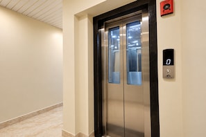 An elevator with a digital display, a fireman's switch, and a wall-mounted control panel. - Hotel O Pix (Jabalpur)