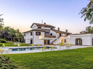 Ein zweistöckiges Haus mit Swimmingpool und Sitzgelegenheit im Freien.