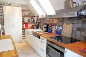 A modern kitchen with white cabinets, a wooden countertop, and a stainless steel range hood. - Holiday home with 3 bedrooms (Westerholz)