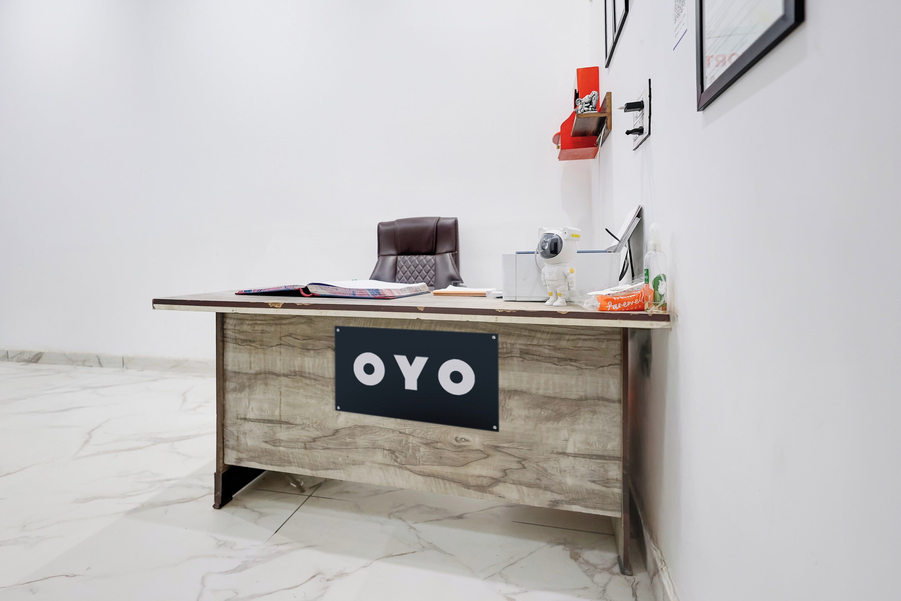 A reception desk with a sign that reads 'OYO' and a small astronaut figurine on top.