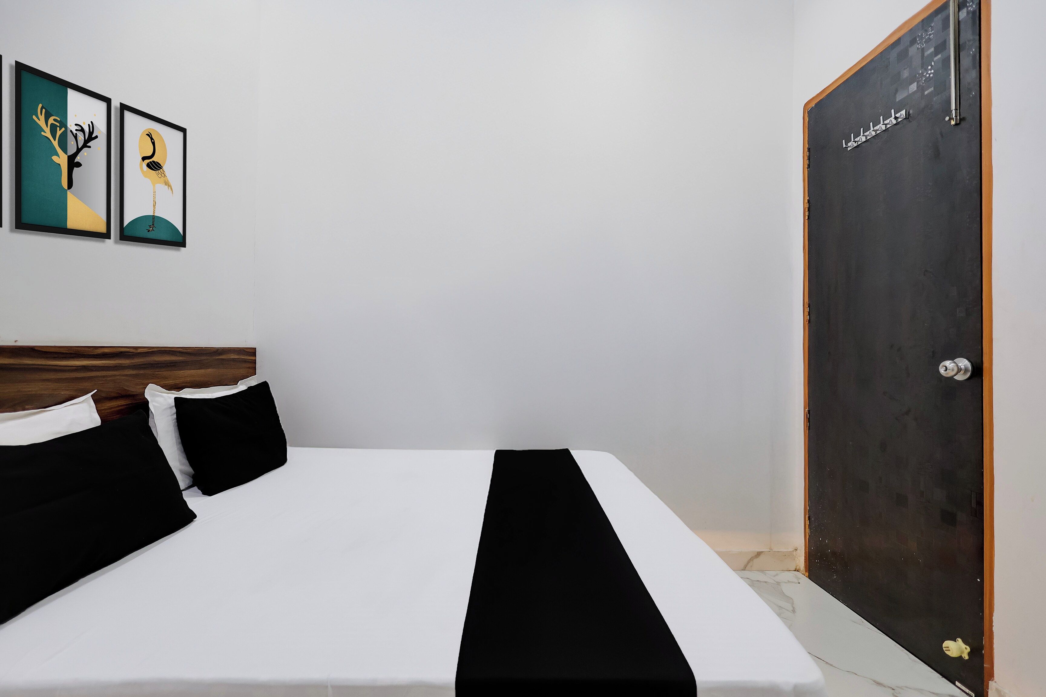A hotel room with a bed, a wooden headboard, a black and white striped bedspread, and a door with a handle.