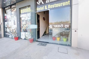 Un hôtel et un restaurant dotés d’un hall d’accueil, de portes vitrées et de plantes en pot à l’extérieur.