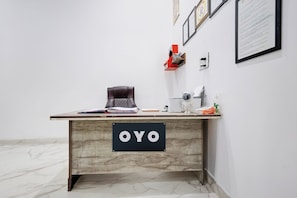 Un bureau en bois sur lequel est posée une plaque portant l’inscription « OYO », dans une pièce aux murs blancs et au sol en marbre.