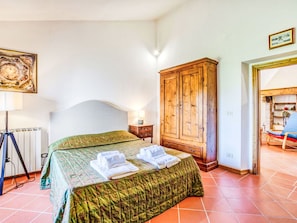 Un dormitorio con una cama, un armario de madera, un radiador y un cuadro en la pared.