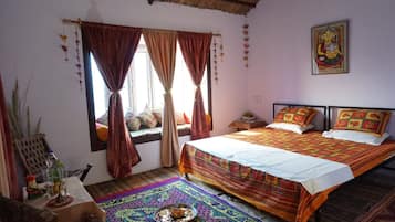 Una habitación con dos camas, una ventana con cortinas, un adorno en la pared y un tapete tradicional en el suelo.
