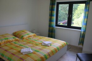 A bedroom with a bed, pillows, a window, and curtains. - Holiday apartment with 2 bedrooms (Heidesee)