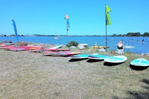 A beach with surfboards and flags, a clear sky, and calm water. - Holiday home in Maasholm with swimming pool (Maasholm)