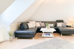 Ein modernes Wohnzimmer mit einem Ecksofa, einem Couchtisch und einer kleinen Pflanze.
