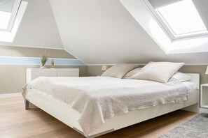 A bedroom with a sloped ceiling, a bed with a white headboard, and a skylight. - Holiday apartment with 1 bedroom (Timmendorfer Strand)