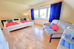 Een slaapkamer met een bed, een bank, een lamp en een raam met gordijnen.