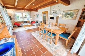 Een gezellige kamer met een houten eettafel, stoelen, een bank en een open haard.