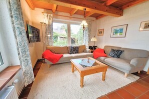 Een gezellige woonkamer met een bank, een bijzettafeltje en een televisie.
