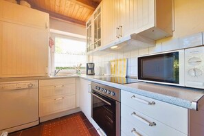 Een keuken met witte kastjes, een magnetron, een oven en een koffiezetapparaat.