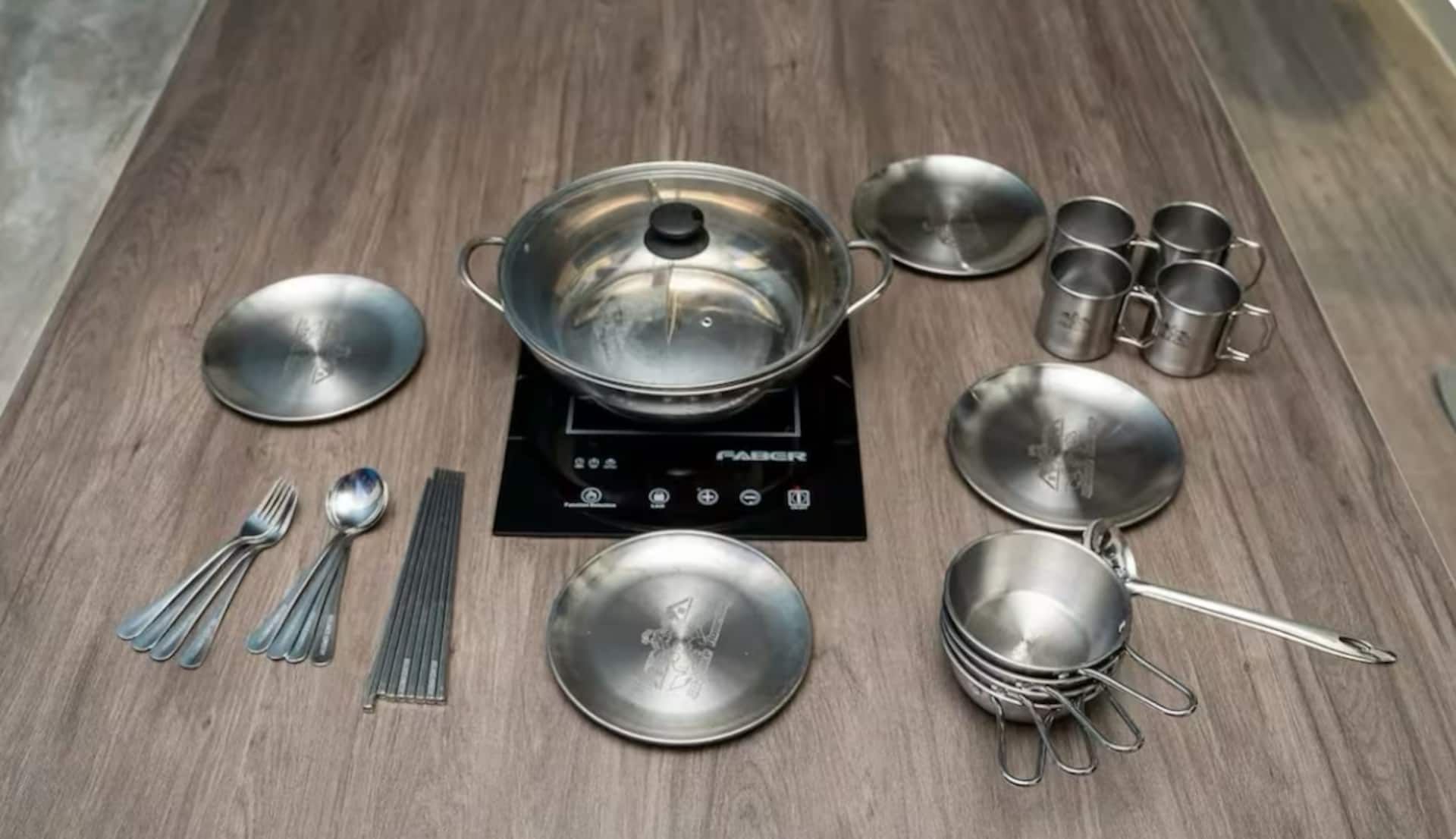 A kitchen setup with a stove, pots, pans, and utensils.