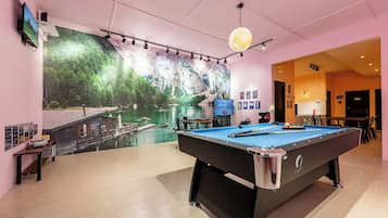 Una mesa de billar en una habitación con un gran mural de un lago y montañas.