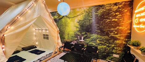 A tented room with a bed, chairs, and a table.