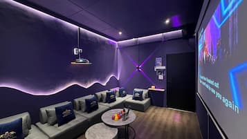 Un salón moderno con sofás, una mesa de centro y una pantalla grande mostrando la letra de una canción.