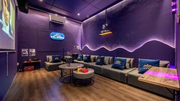 A modern lounge area with sofas, a coffee table, and a projector screen.