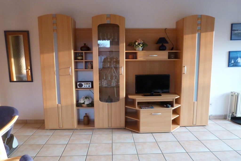 A living room with a television, wooden cabinets, and a tiled floor.