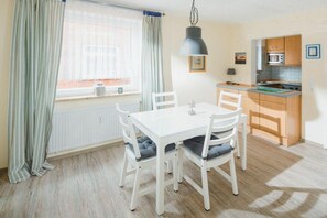 Eine kleine Küche mit Essbereich, einem fensterbepflanzten Fenster und einer Pendelleuchte.