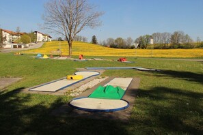 A playground with various play structures, a tree, and a grassy area with yellow flowers. - Dambach with lake view (Füssen)