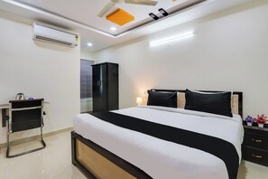 Quarto de hotel moderno com cama, mesas de cabeceira, guarda-roupa e ar condicionado.