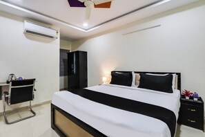 Quarto de hotel com cama, mesa de cabeceira, luminária e ar condicionado.