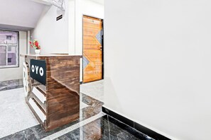 Bancada de recepção com uma placa indicando 'OYO' e uma porta de madeira com o número '407' em cima.