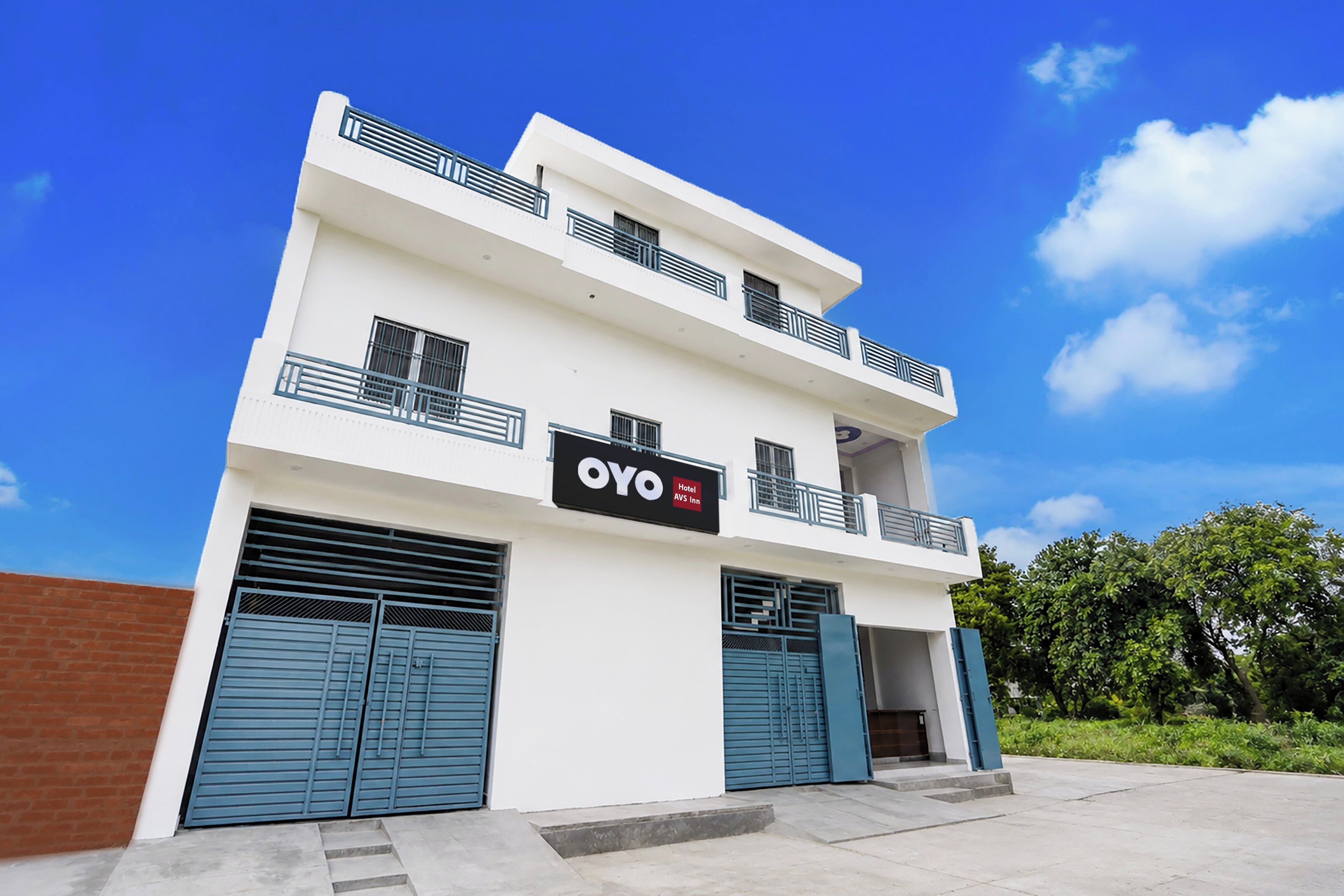 Un edificio de dos pisos con un letrero que dice 'OYO Hotel AVS Inn' en la fachada.