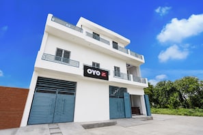 Un edificio de dos pisos con un letrero que dice 'OYO Hotel AVS Inn' en la fachada.