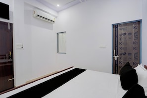 Una habitación de hotel con cama, unidad de aire acondicionado, una puerta con el logotipo Kybod y un interruptor de luz montado en la pared.