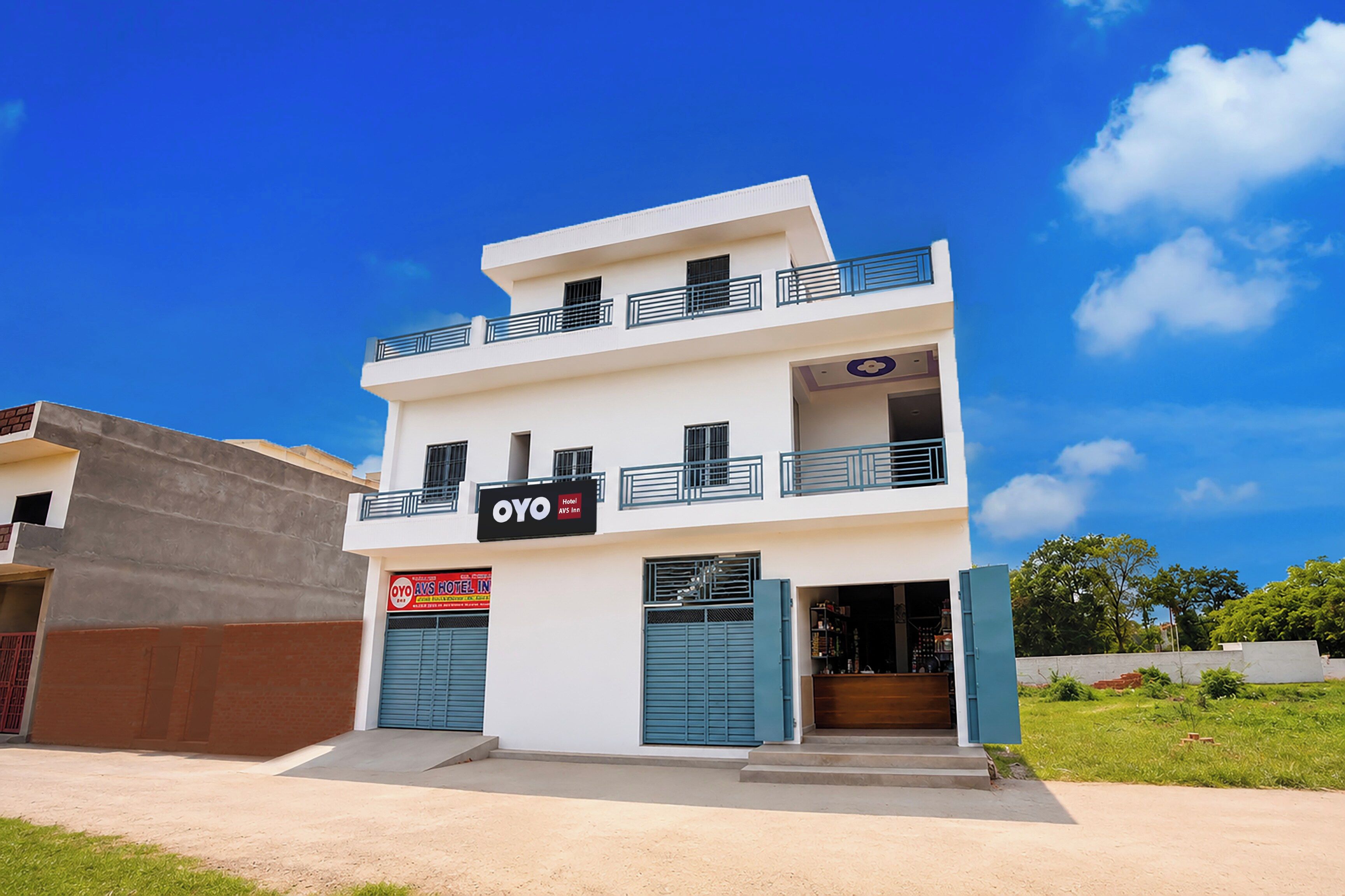 A two-story hotel with a flat roof, balconies, and a sign for 'OYO AVS Inn'.