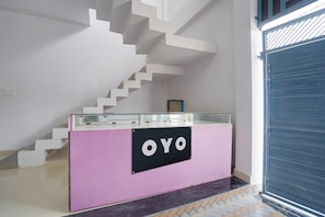 Un mostrador de recepción con un cartel que dice 'OYO' en un interior moderno con una escalera.