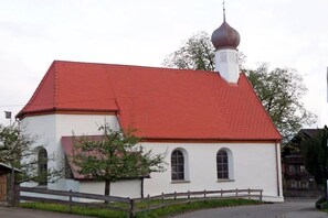 A small building with a red roof and a white facade, featuring a single arched window and a small bell tower. - 3 in the Lingenhöl house (Sonthofen)