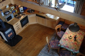 A compact kitchen with a wood stove, microwave, and sink. There is a dining area with a table and chairs. - Holiday home in Zingst with barbecue (Zingst)