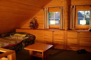 A cozy cabin interior with a bed, a small table, and a window with curtains. - Holiday home in Zingst with barbecue (Zingst)