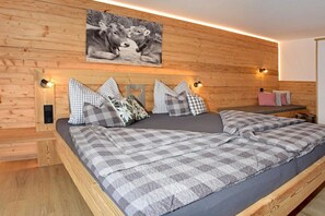 A wooden-paneled room with a bed, pillows, and a wall-mounted light fixture. - Holiday apartment with 1 bedroom (Immenstadt-Bräunlings)