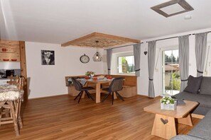 A cozy living room with a sofa, a dining area with a table and chairs, and a kitchen area with wooden cabinets and a coffee machine. - Holiday apartment with 1 bedroom (Immenstadt-Bräunlings)