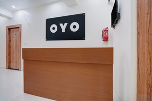 A reception desk with a sign that reads 'OYO' and a fire extinguisher mounted on the wall. - Hotel O Sapphire Grand (Lucknow)