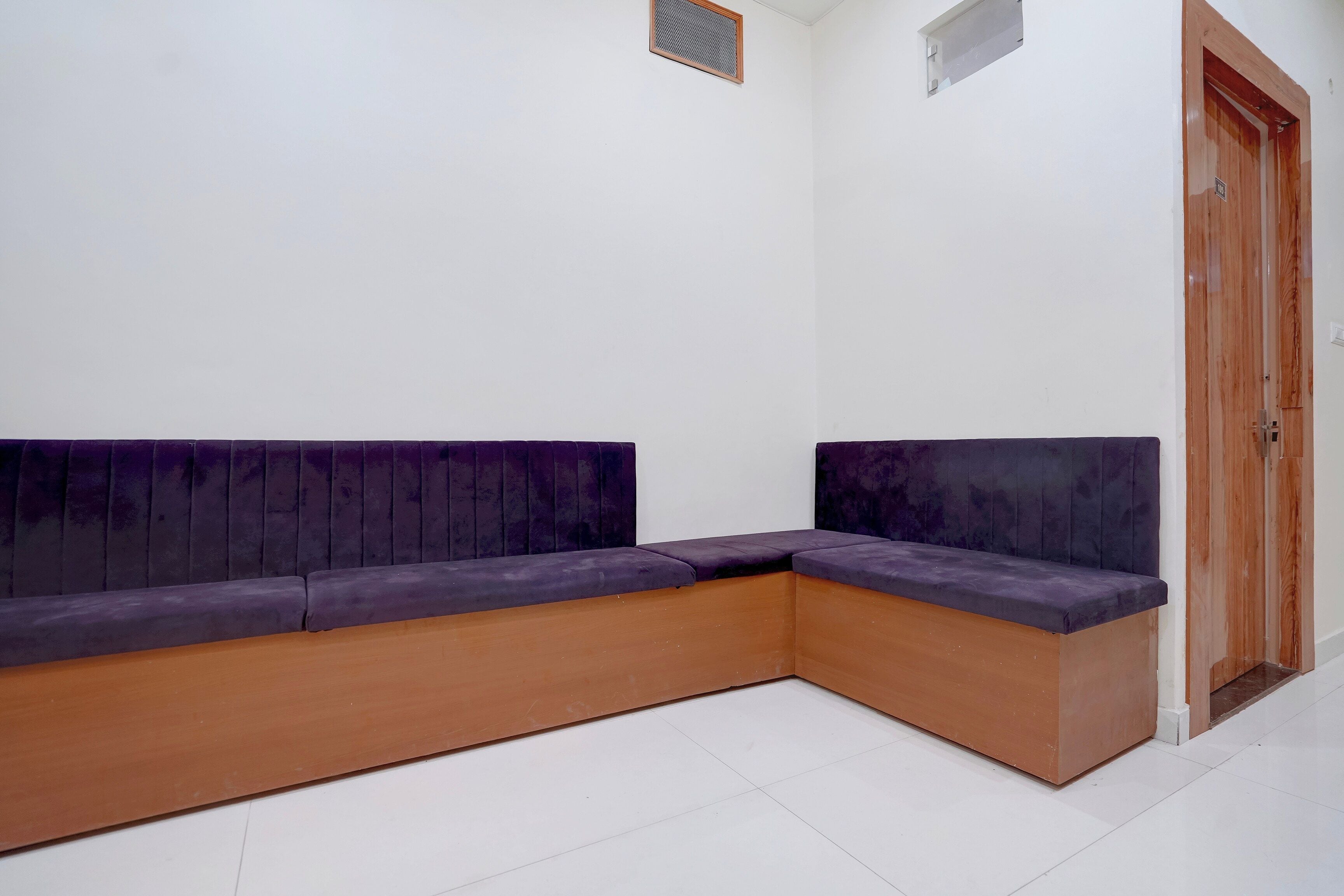 A corner seating area with a wooden bench and a purple cushioned backrest.