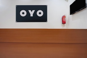 Ein Schild mit dem Wort 'OYO', ein an der Wand befestigter Feuerlöscher und eine Holzvertäfelung darunter.