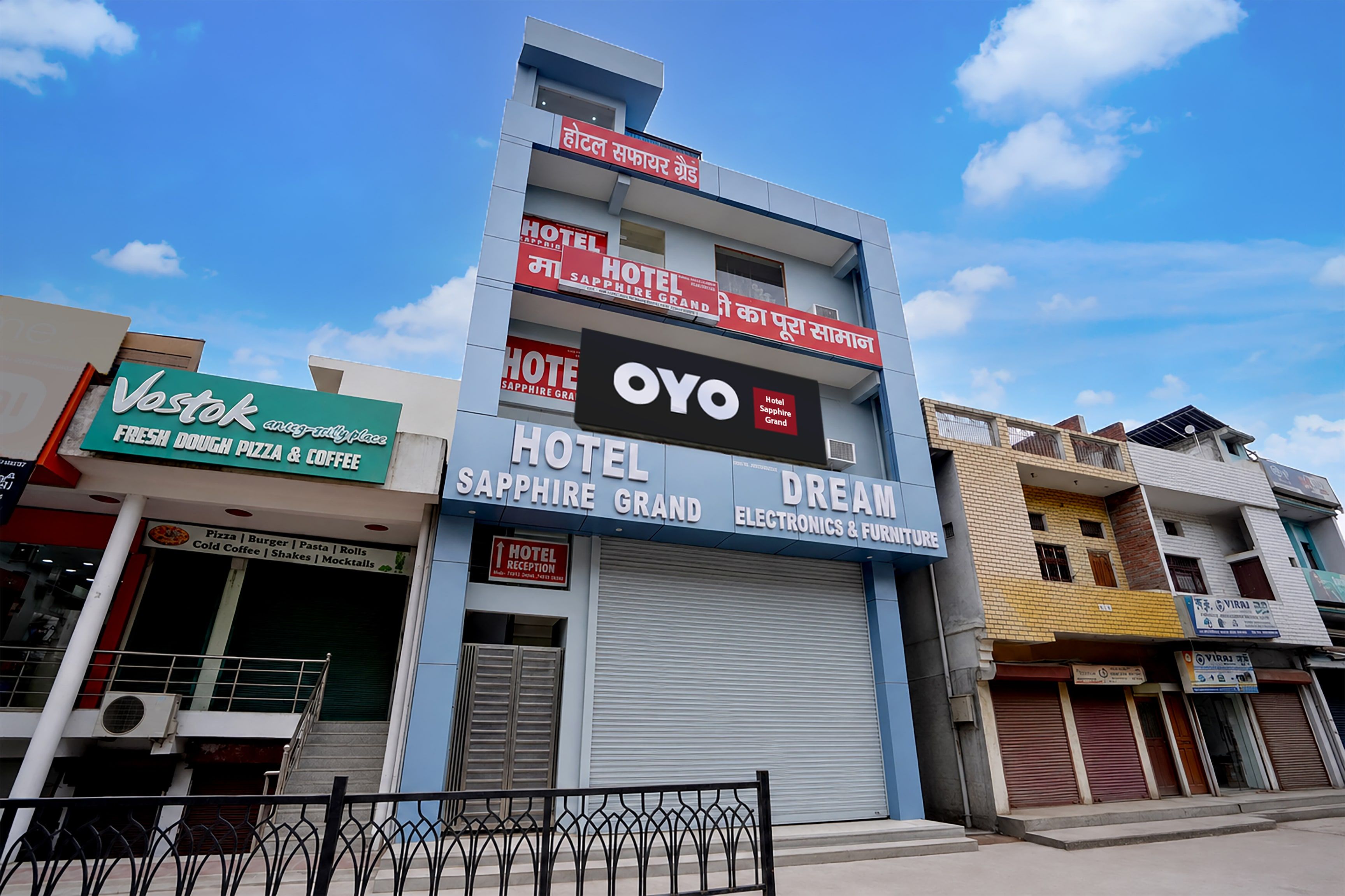 Un hotel con un letrero que dice 'Hotel Sapphire Grand' y 'Dream Electronics & Furniture' en la fachada.