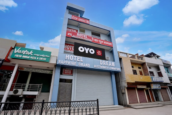 Un hotel con un letrero que dice 'Hotel Sapphire Grand' y 'Dream Electronics & Furniture' en la fachada.