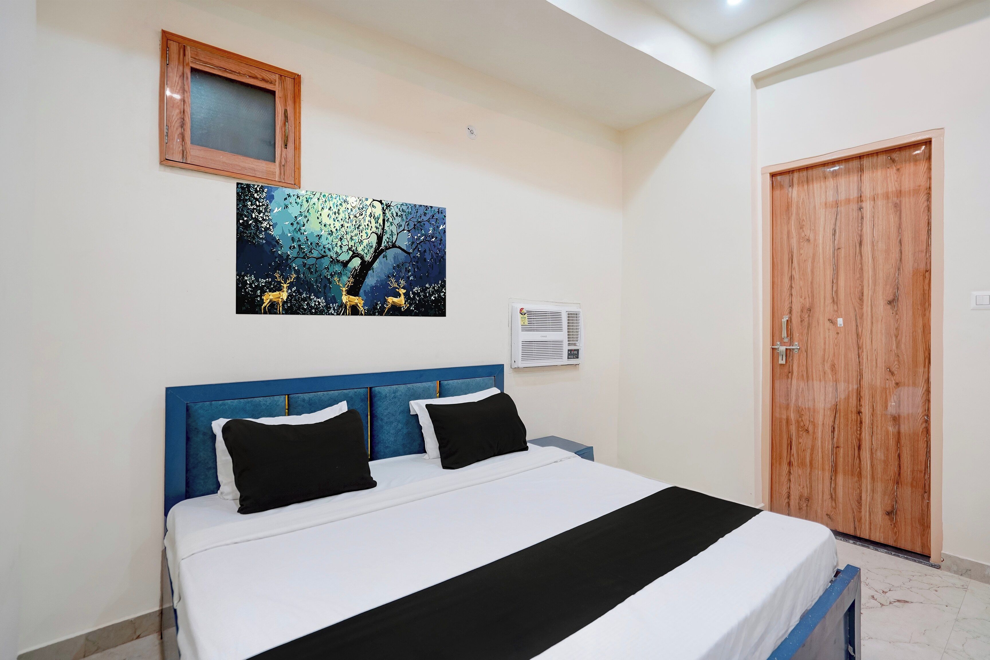 Un dormitorio con cama, un cuadro, un equipo de aire acondicionado y una puerta de madera.